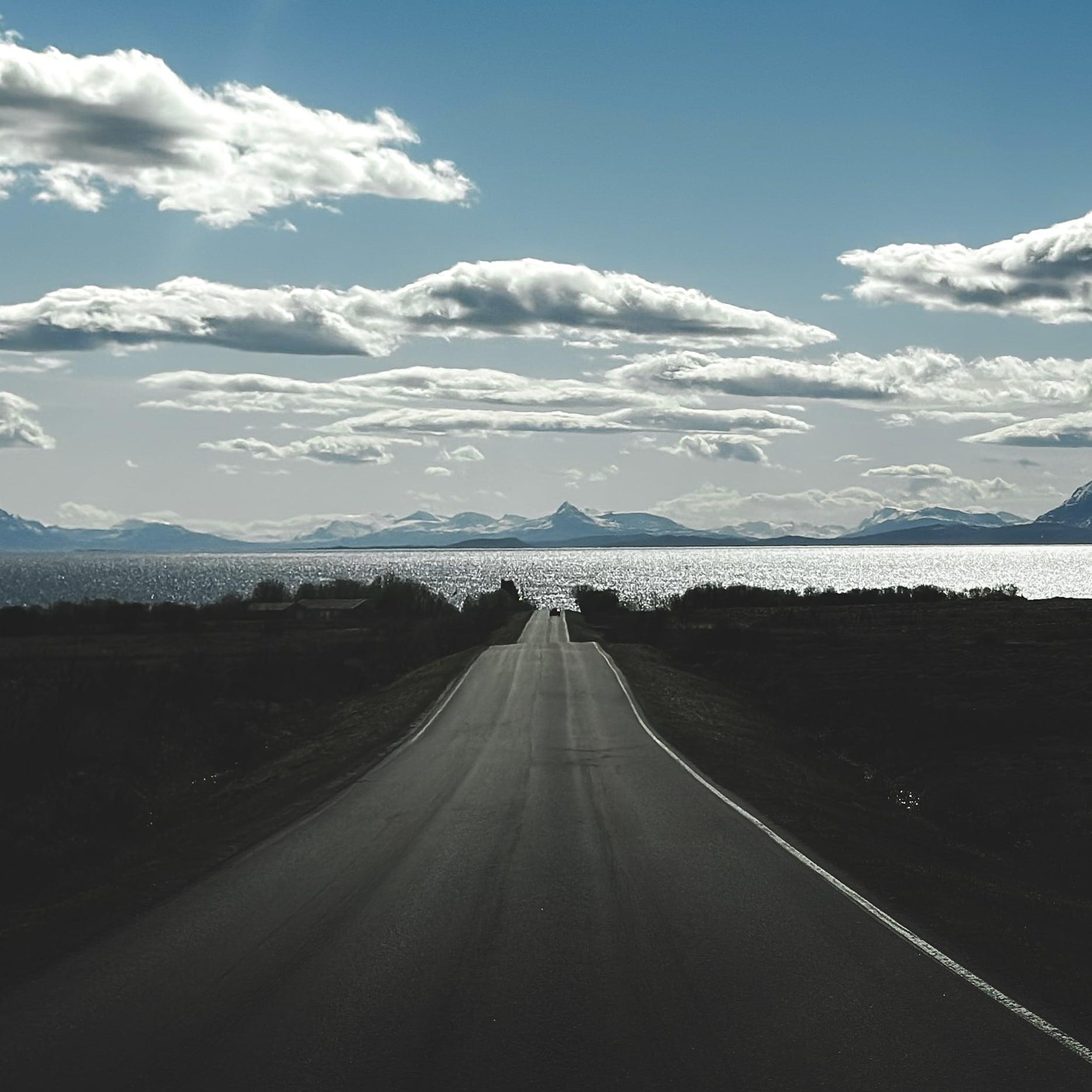 Einsame Landstraße mit Blick auf Fjord und schneebedeckte Berge
