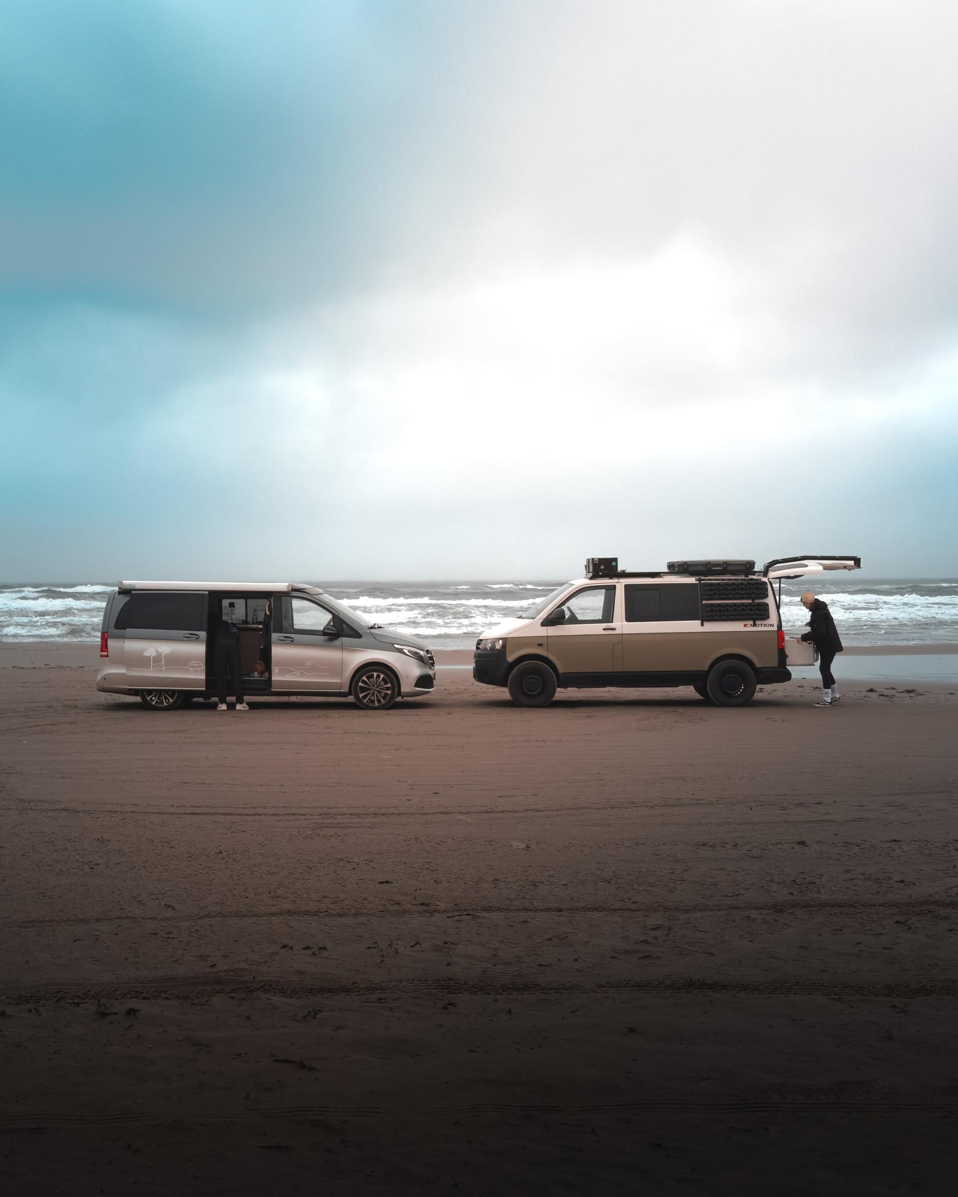 Fernaufnahme von zwei Campern die sich an einem Strand in Dänemark gegenüber stehen