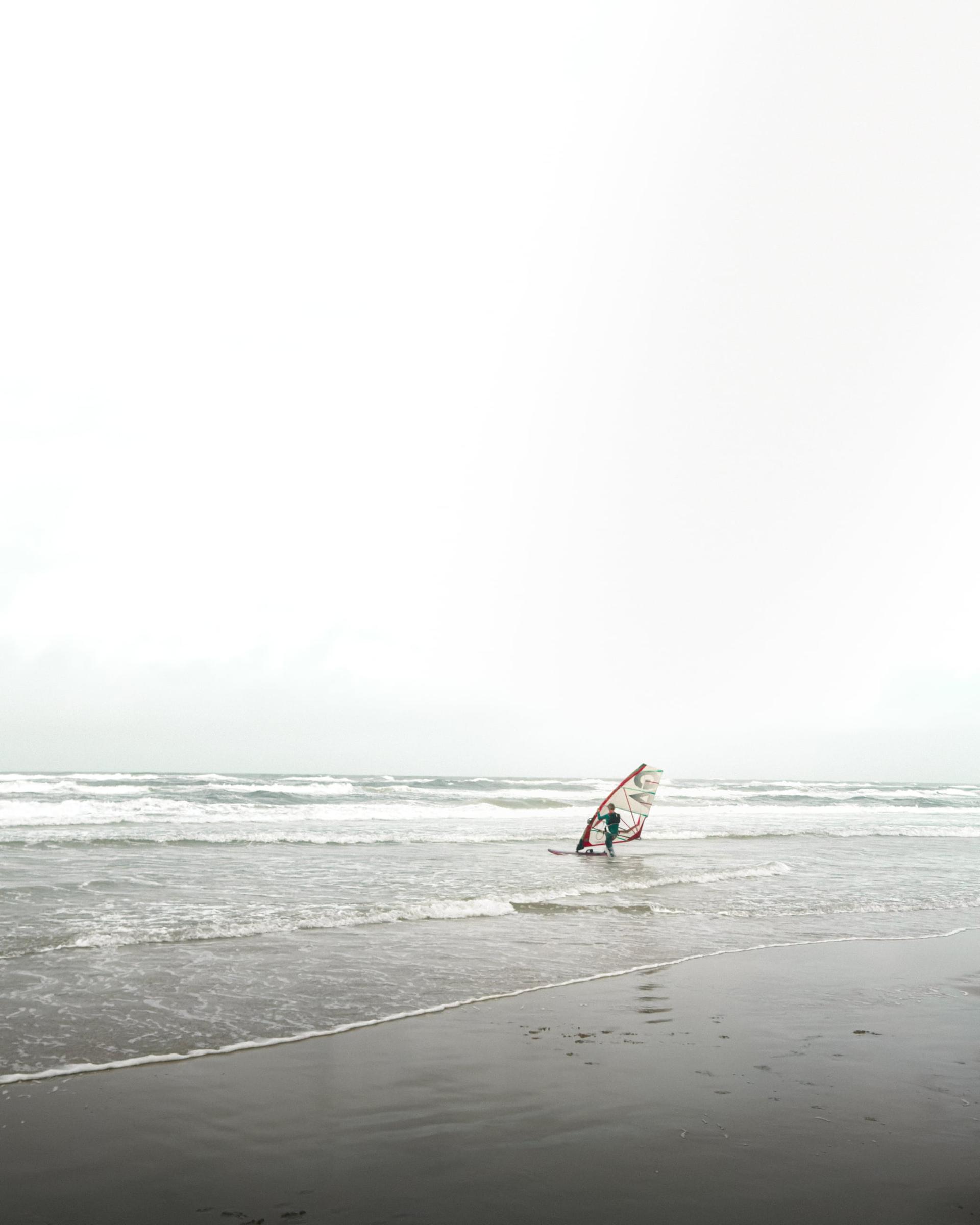 Ein Windsurfer auf dem Weg in die Wellen