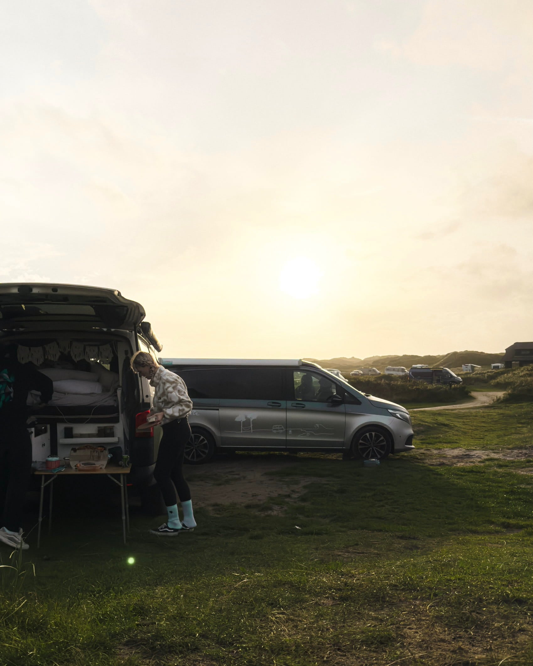 Camper am Stellplatz in den Dünen bei Sonnenuntergang